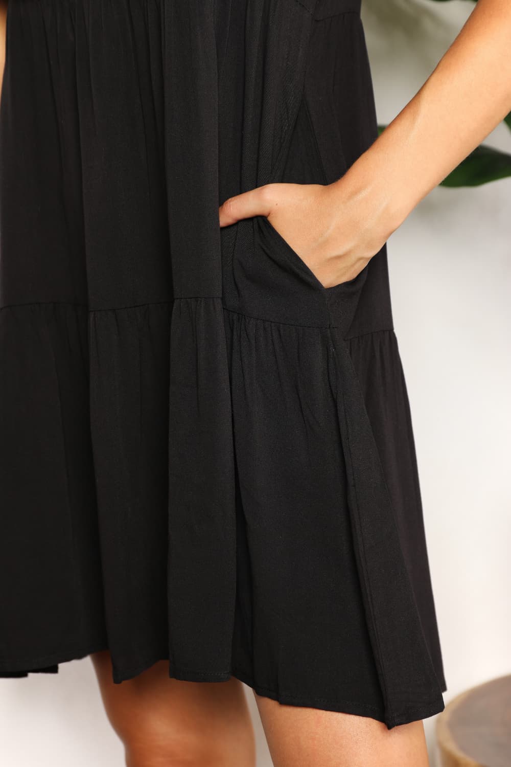 "Close-up of the side pocket and tiered skirt of the black Mandy mini dress."