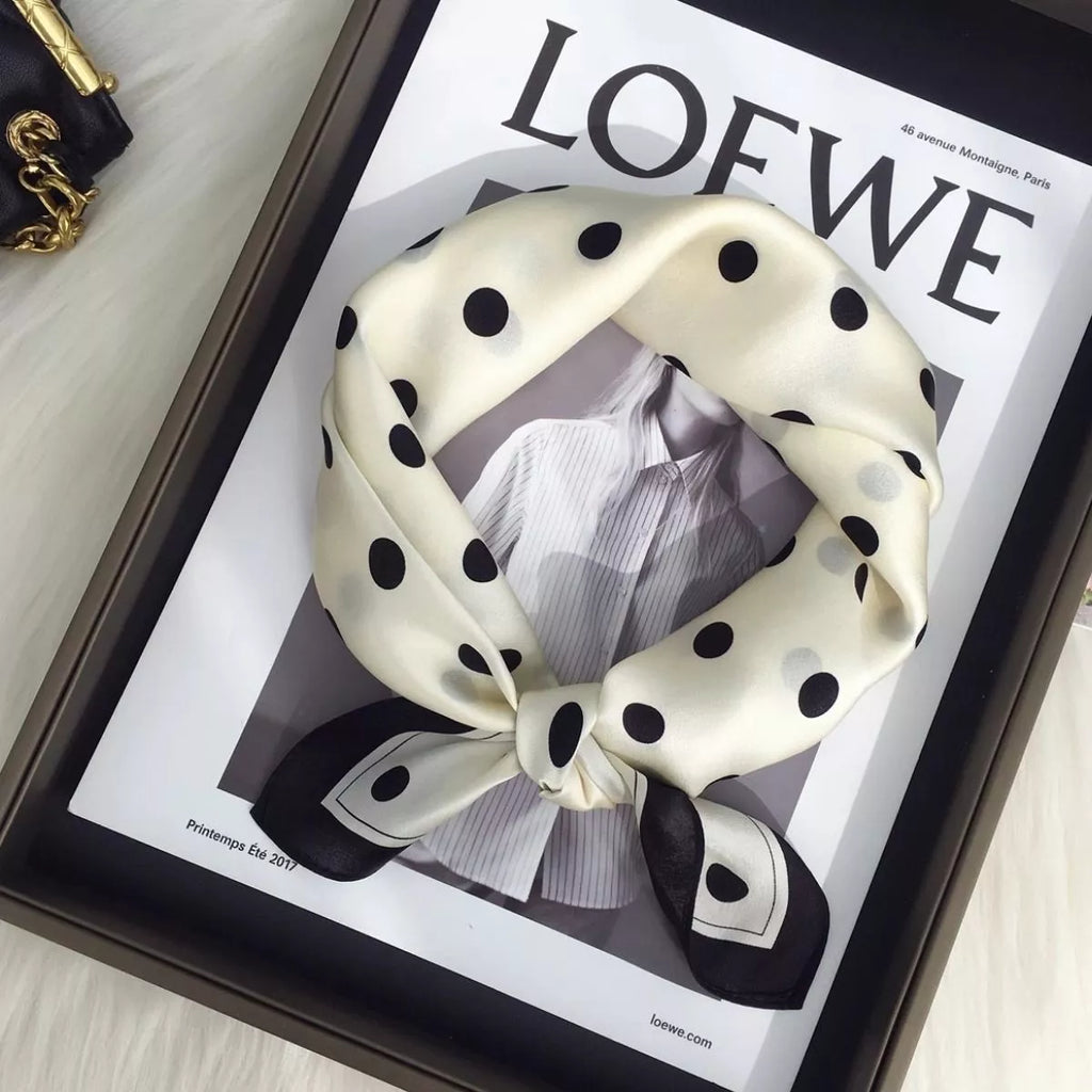 Cream white silk scarf with black polka dots tied into a loop