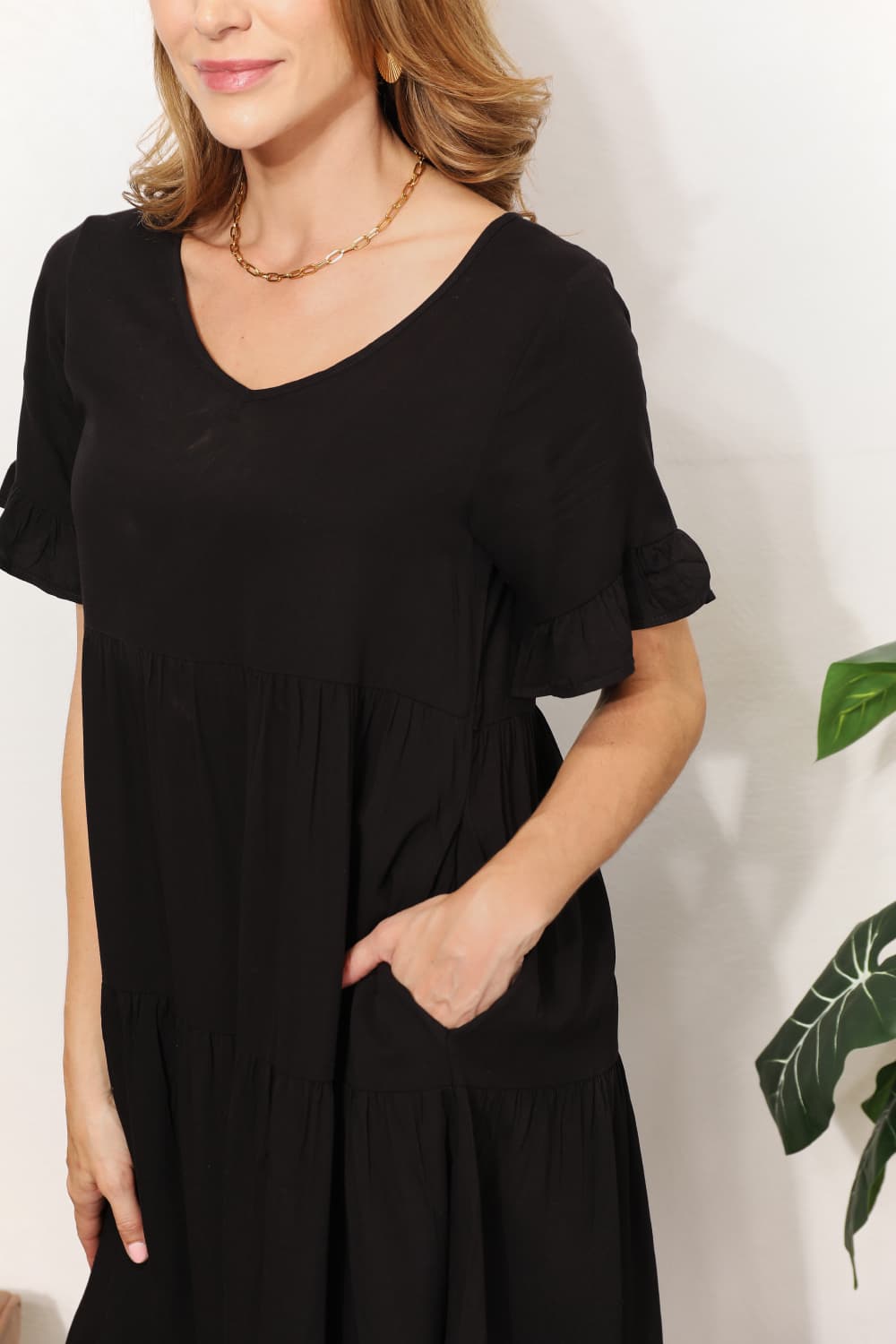 "Close-up of the V-neckline and side pocket of the black Mandy tiered mini dress."