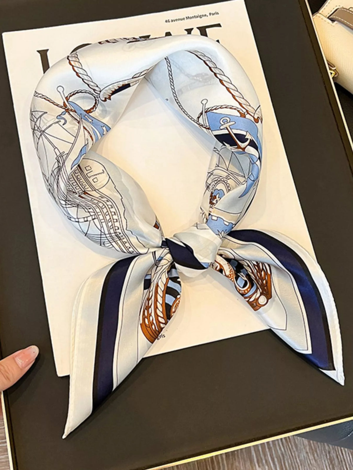 Ivory nautical print square scarf tied in a loop on a magazine.