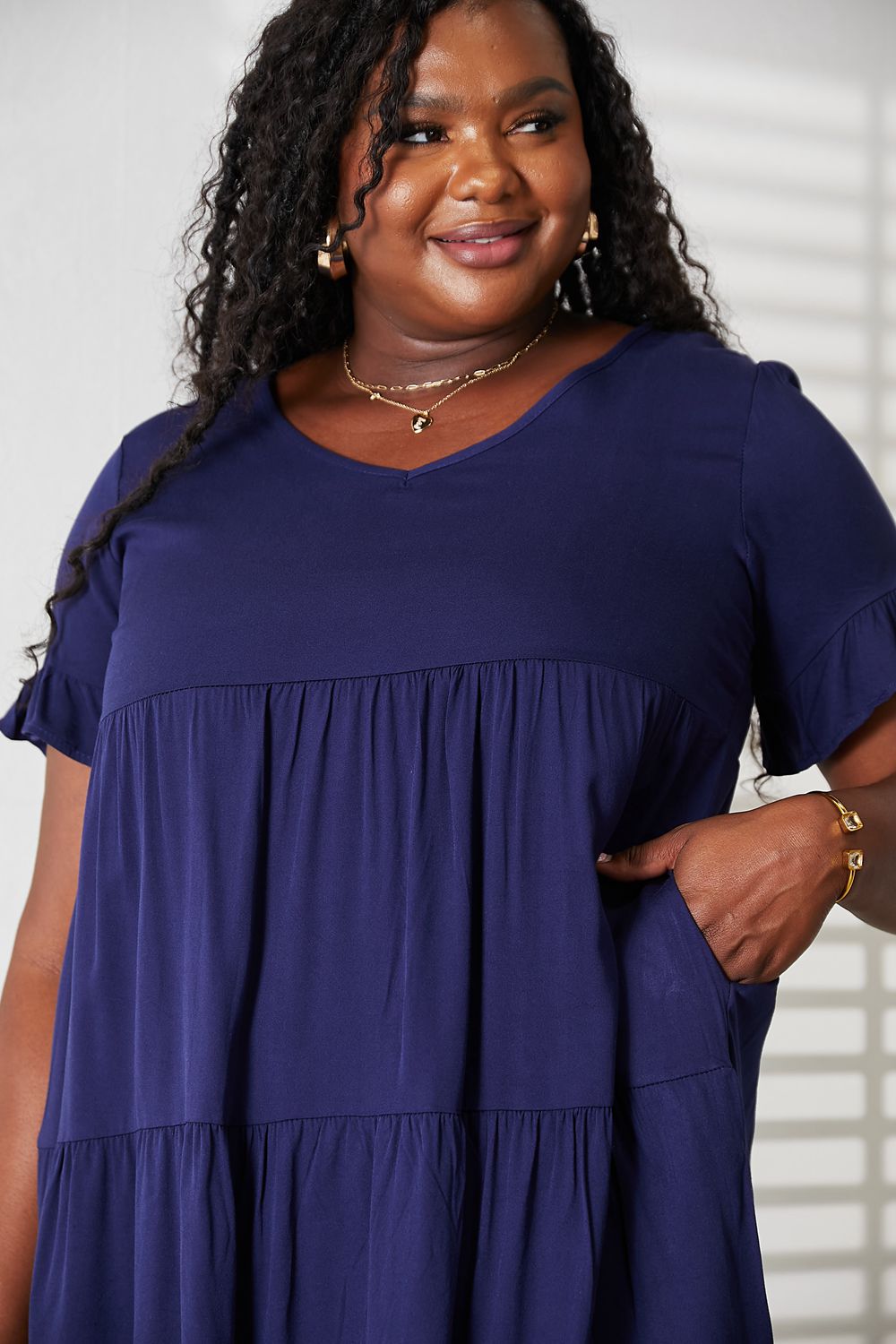 Model wearing the dark blue Mandy tiered V-neck mini dress with hands in pockets