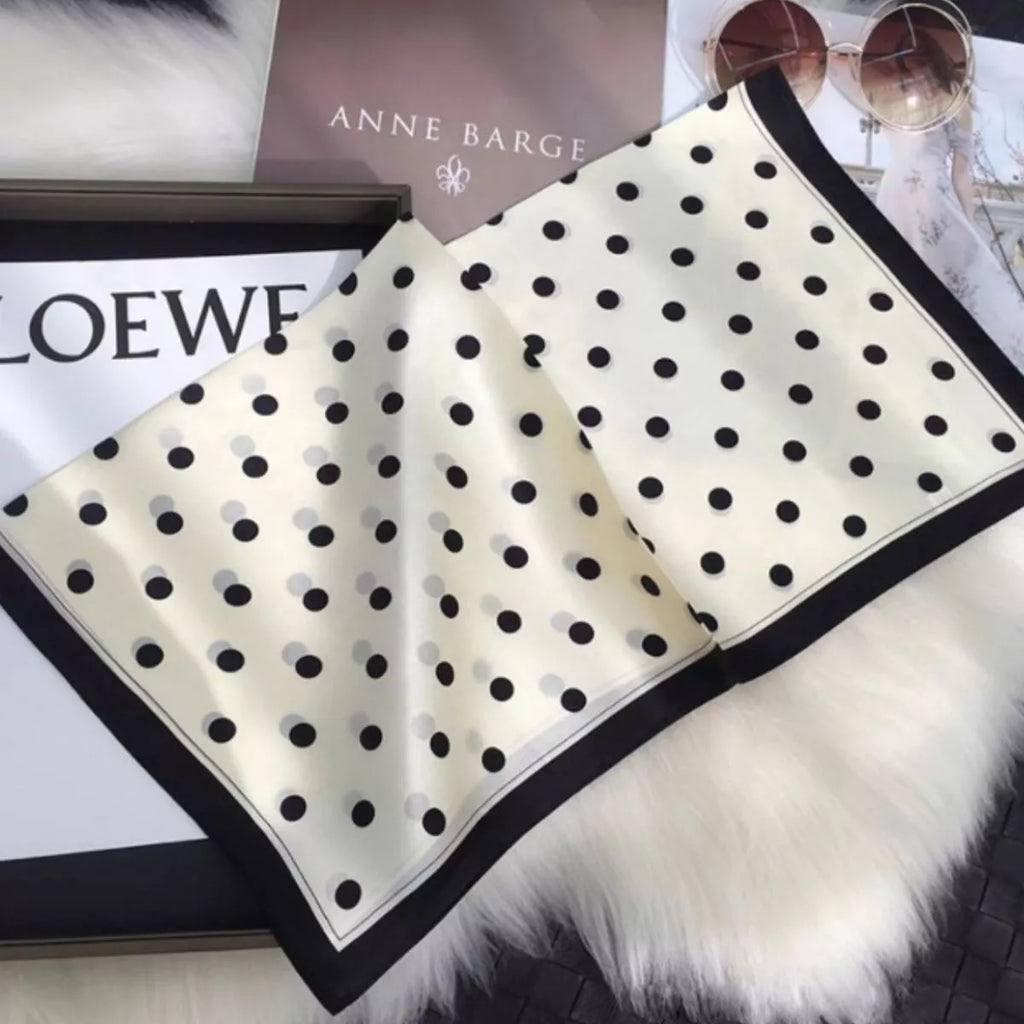 Cream white polka dot silk scarf spread out to show its black border