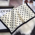 Cream white polka dot silk scarf spread out to show its black border
