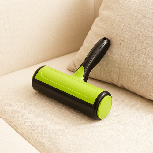 Green and black two-way pet lint roller resting on a cream sofa beside a cushion