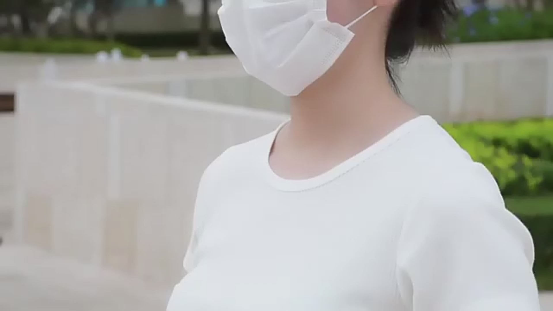 White wearable neck fan demonstration video, showing the curved neckband, side vents and dark circular control.